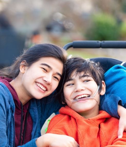 disabled young man in wheelchair smiling at camera with sibling