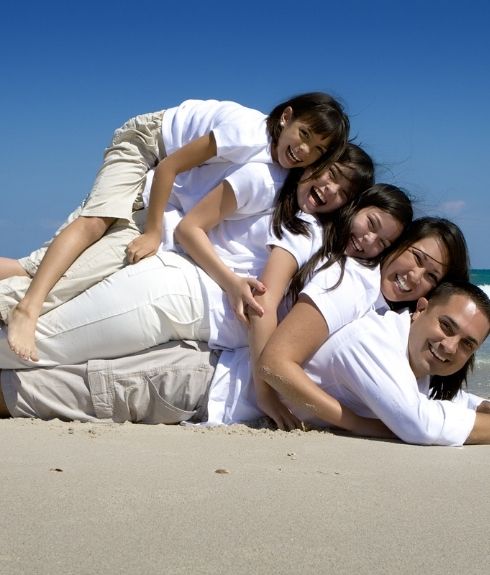 hispanic family on the beach in a pyramid smiling at camera