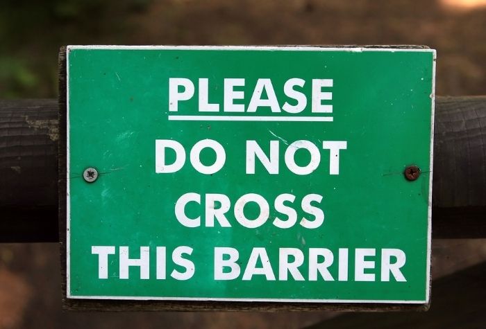 rustic green sign that says please do not cross this barrier