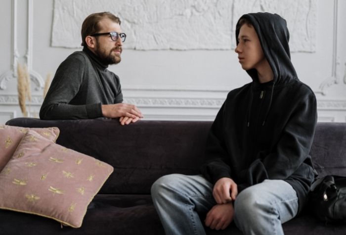 man and teenage boy sitting on couch talking