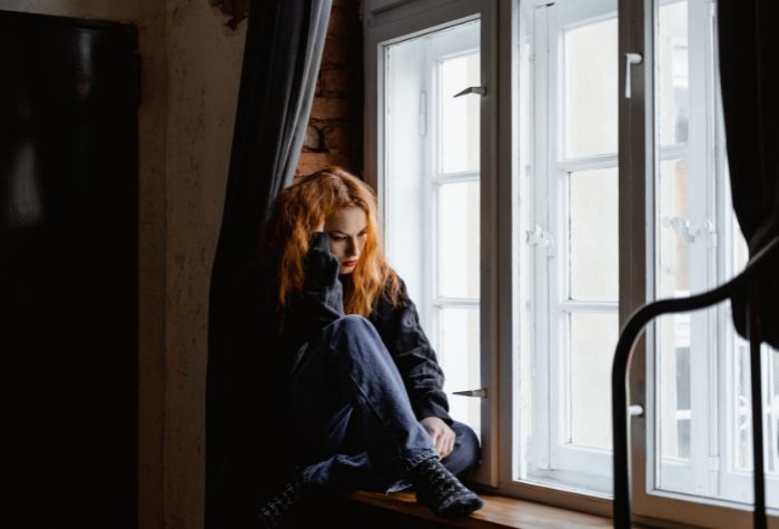 young girl looking out window sad thoughtful