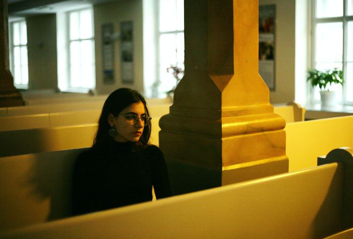 Thoughtful young woman sitting alone in a pew in a church