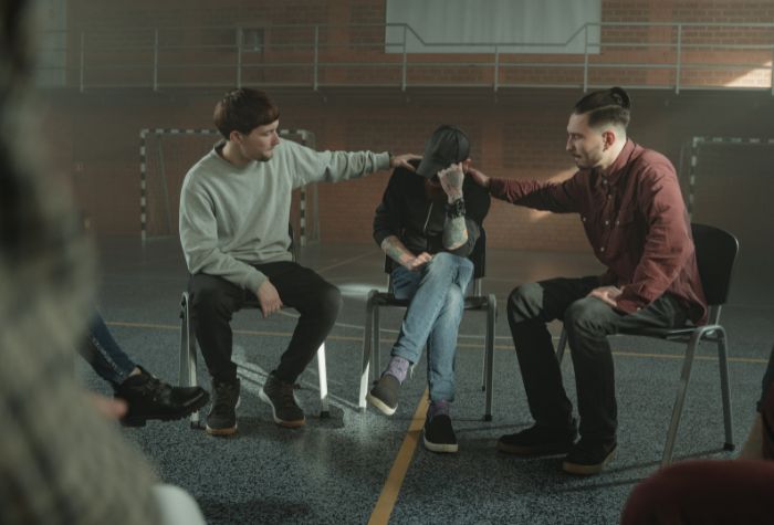 A member of a support group is comforted by two other members.