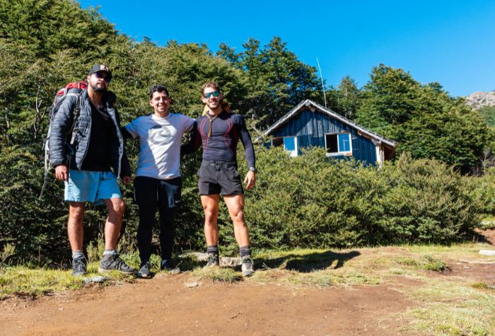 three young active men posing for a photo together outdoors in front of a navy blue house.