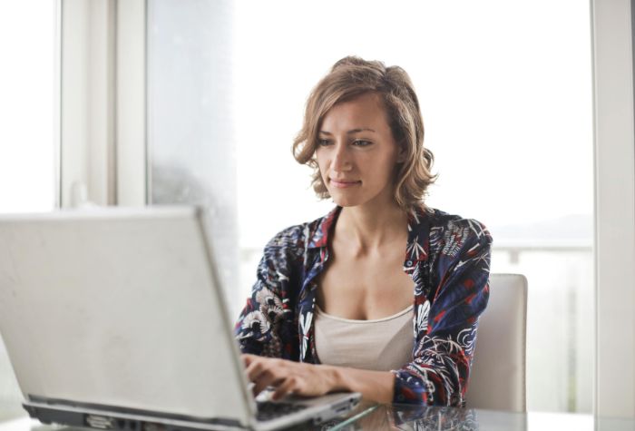 blond woman using laptop computer in room filled with natural light